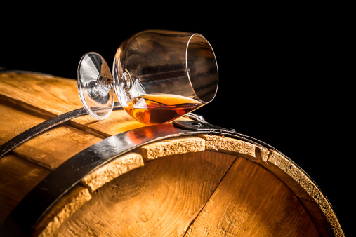 Glass of cognac on the vintage barrel.